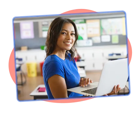 Educator in a classroom holding a laptop